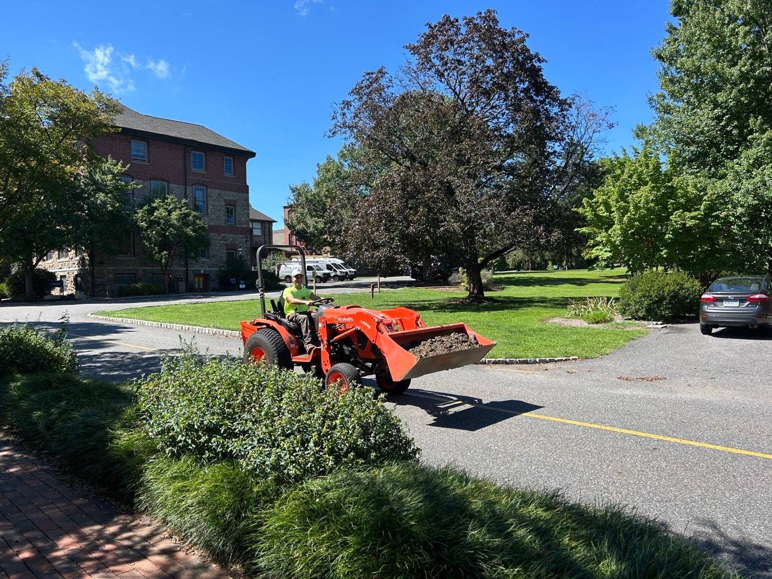 Dragan Landscaping crew operating a tractor to deliver mulch on a commercial property